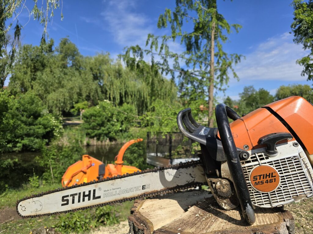 STIHL láncfűrész rönkön, háttérben ágaprító gép